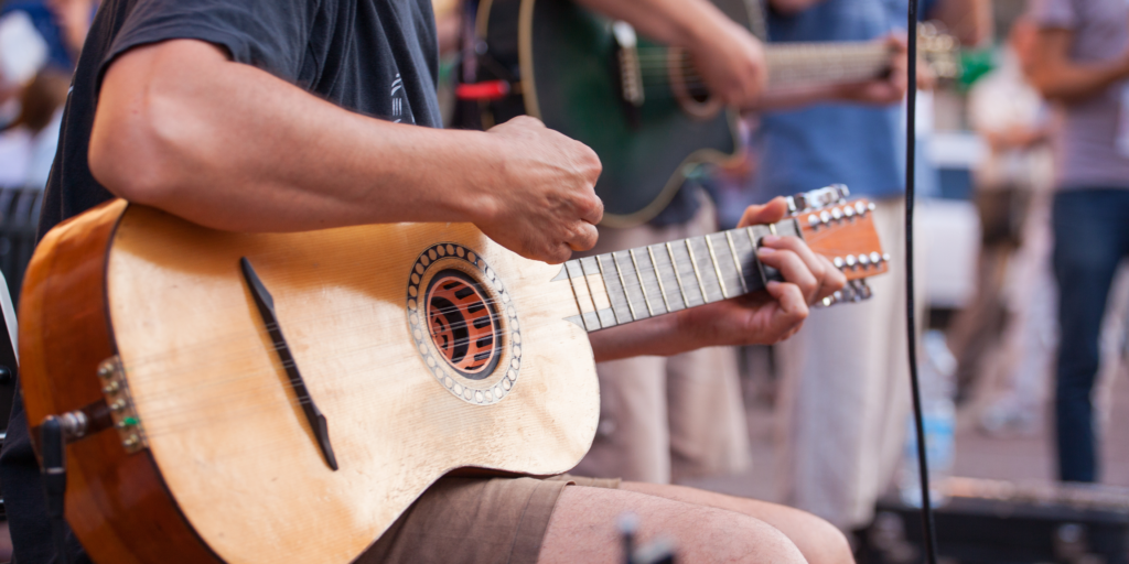 Summer concert event, an acoustic band playing focused on a guitarist 